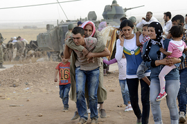 Syrian Kurds walk after crossing into Turkey at the Turkish-Syrian border, near the southeastern town of Suruc in Sanliurfa province