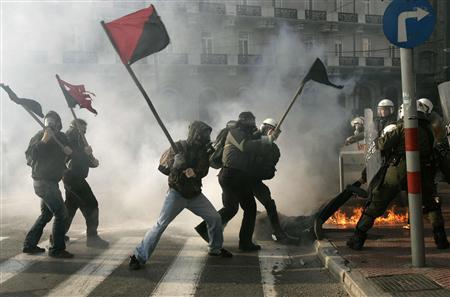 Self-styled anarchists armed with wooden sticks fight against the police in an attempt to release a detained comrade (on the floor) in a cloud of tear gas outside the Greek Parliament in Athens in this February 22, 2007 file photo. REUTERS/Yannis Behrakis/Files