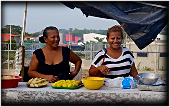 Dayanera and her daughter at the stand where they sell food to neighbours; opportunities to make money are limited, and often confined to the community itself. [Julia Zulver/Al Jazeera]