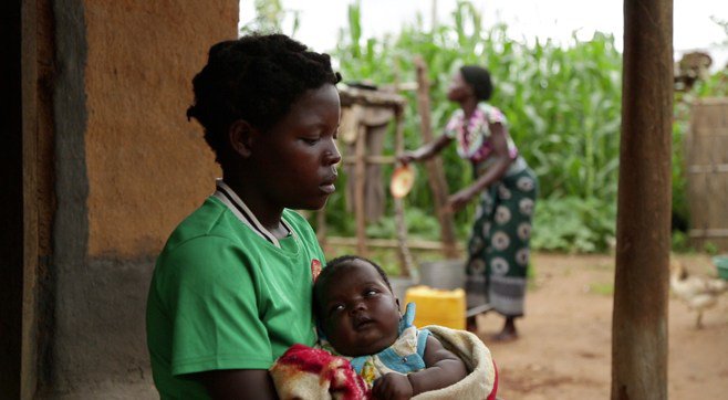 A 14-year-old girl holds her baby at her sister's home 