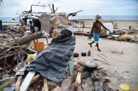 A woman prepares food near her destroyed house in the aftermath of Hurricane Matthew in the commune of Roche-a-Bateaux, southwest Haiti, on October 18, 2016. Food, medicine and other essential aid has been slow to reach areas slammed by Hurricane Matthew. Some desperate Haitians have taken to blocking parts of the road crossing the southern peninsula to intercept humanitarian convoys, in some cases looting them. / AFP PHOTO / HECTOR RETAMAL