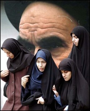 Iranian university students, wearing the Islamic veil, make their way, in front of a picture of late revolutionary founder, Ayatollah Ruhollah Khomeini, inside the campus of Tehran University, in Iran, Sunday, Nov. 9, 2003. Iranian university students marked the first anniversary of a death sentence against one of their professors Sunday by condemning unelected hard-liners and criticizing President Mohammad Khatami's inability to fulfill promises of democratic reforms. Hashem Aghajari, a history professor at Tehran's Teachers Training University was sentenced to death by a court in western Iran last year over charges of insulting Islam and questioning the rule of hard-line clerics. The sentence prompted the biggest student protests in Iran in three years. Iran's Supreme Court lifted the death sentence in February. (AP Photo/Vahid Salemi)